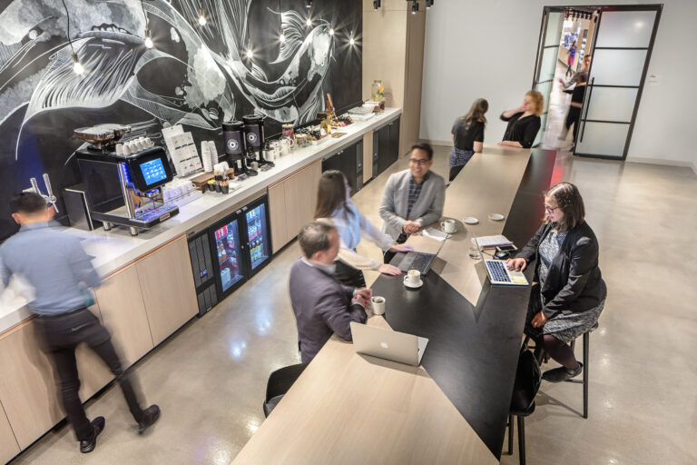 group of businesspeople sitting around counter working on laptops