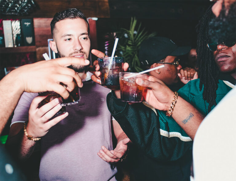 A group of people clinking their glasses together in a "cheers" at a bar
