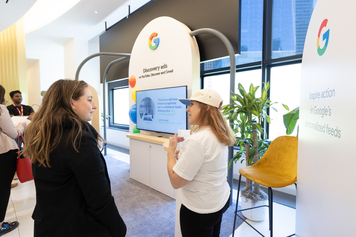Two women stand in front of an activation display by Google