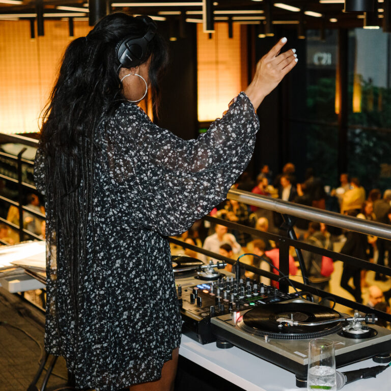 A DJ stands, playing music, at Convene One Liberty Plaza