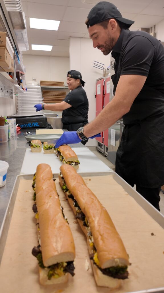 Convene CEO and executive chef prepare vegetarian sandwiches in a commercial kitchen.