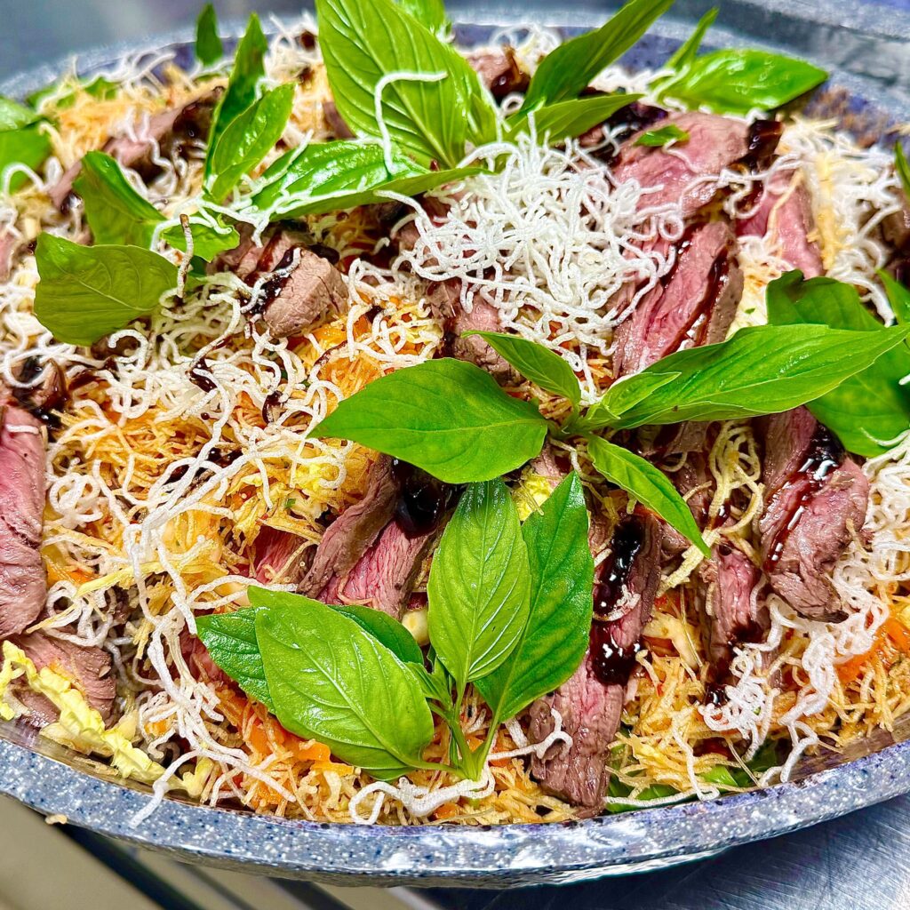 Siam beef steak salad with crispy noodles in stone platter by Convene chefs. 