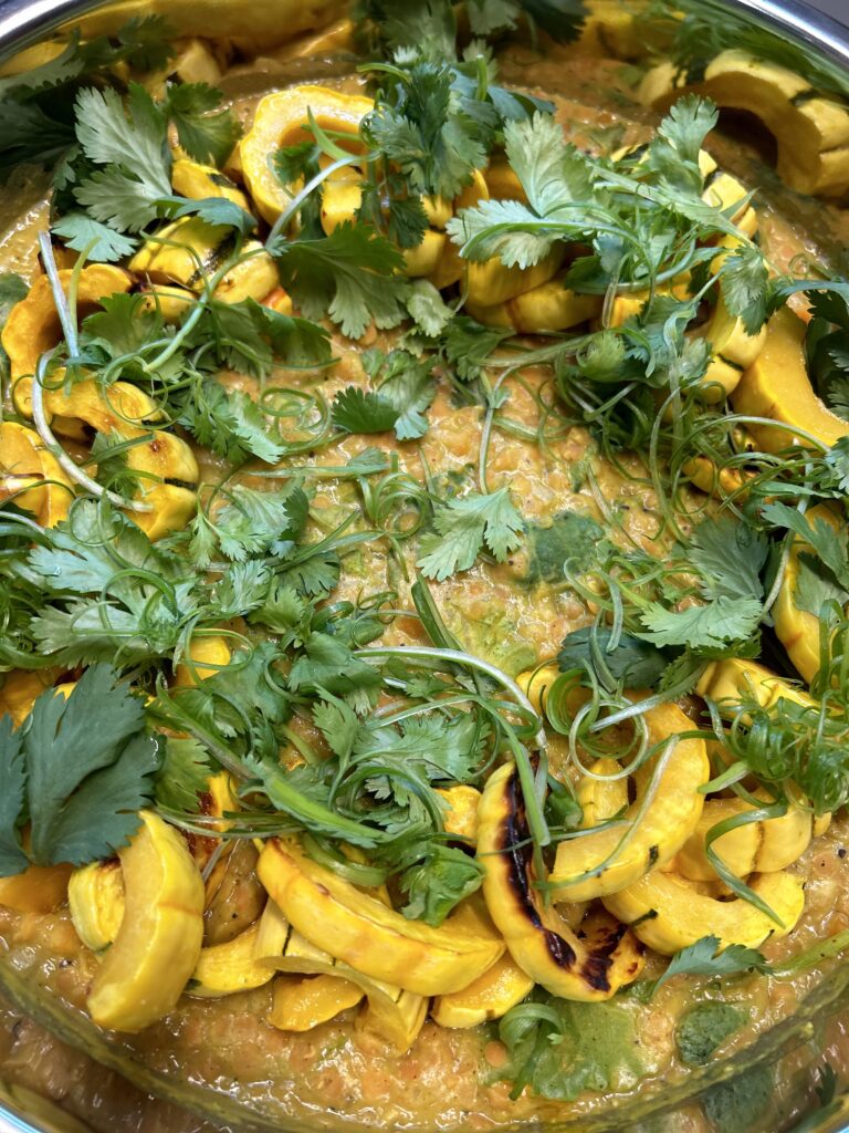 Springs of cilantro over yellow squash and mullifatawny lentils by Convene chefs. 