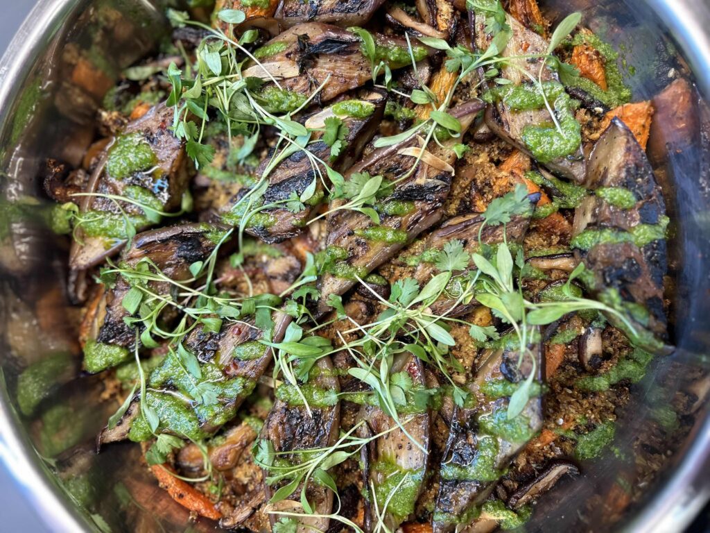 Espelette-spiced eggplant with cauliflower pilaf in metal chafing dish with herb garnish. 