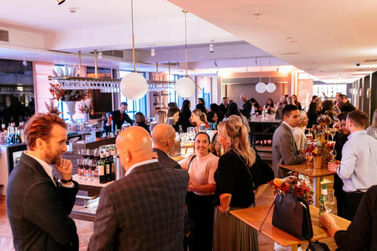 People gathering in the Coade Room etc.venues County Hall with drinks and modern pendant lamps from ceiling.