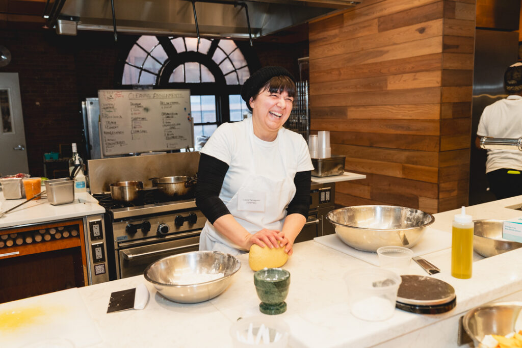 Convene and Hot Bread Kitchen partnership, image shows team member working on a pasta dough in the kitchen.